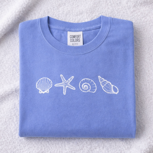 Folded hydrangea shirt with white shell and starfish designs on a textured surface