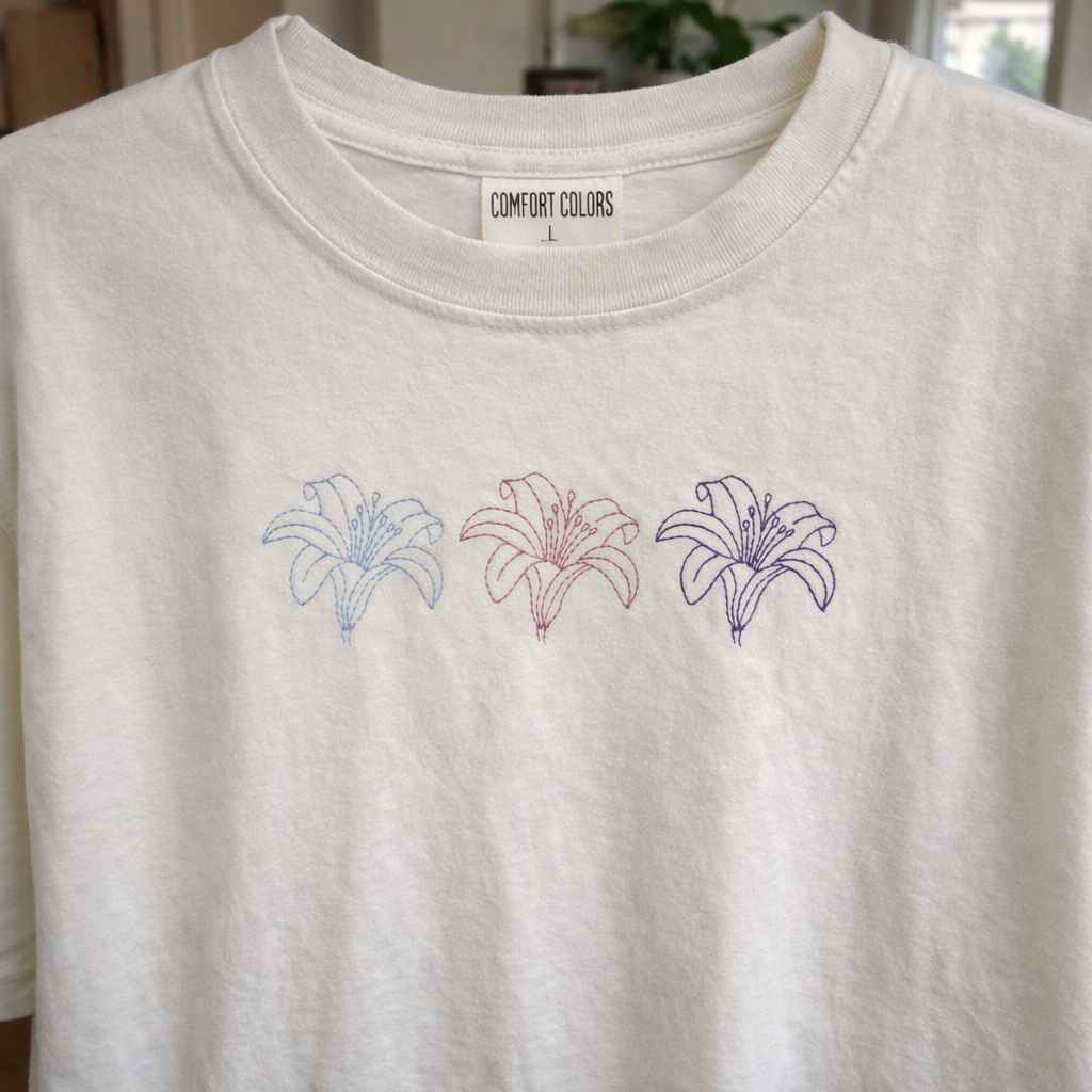 Ivory t shirt with embroidered lilies on a neutral background