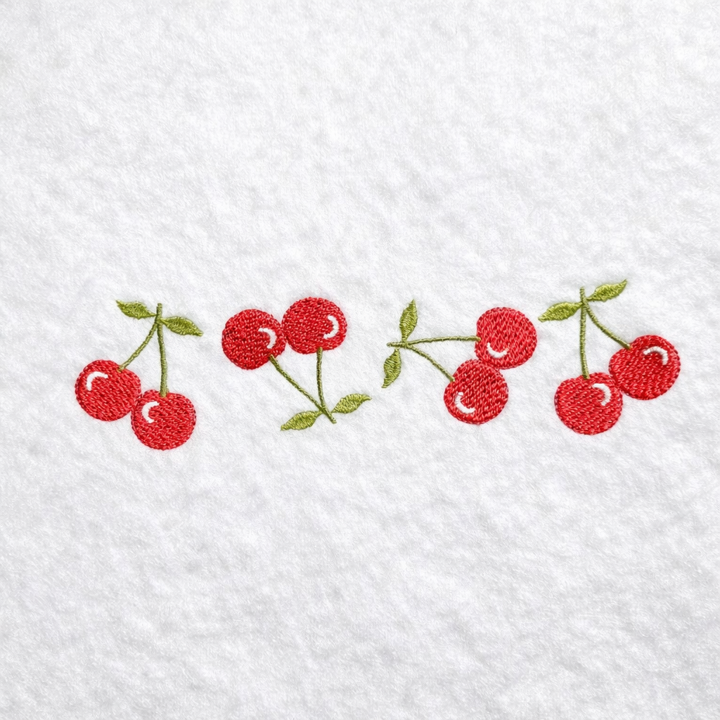 Embroidered cherries on a white fabric background