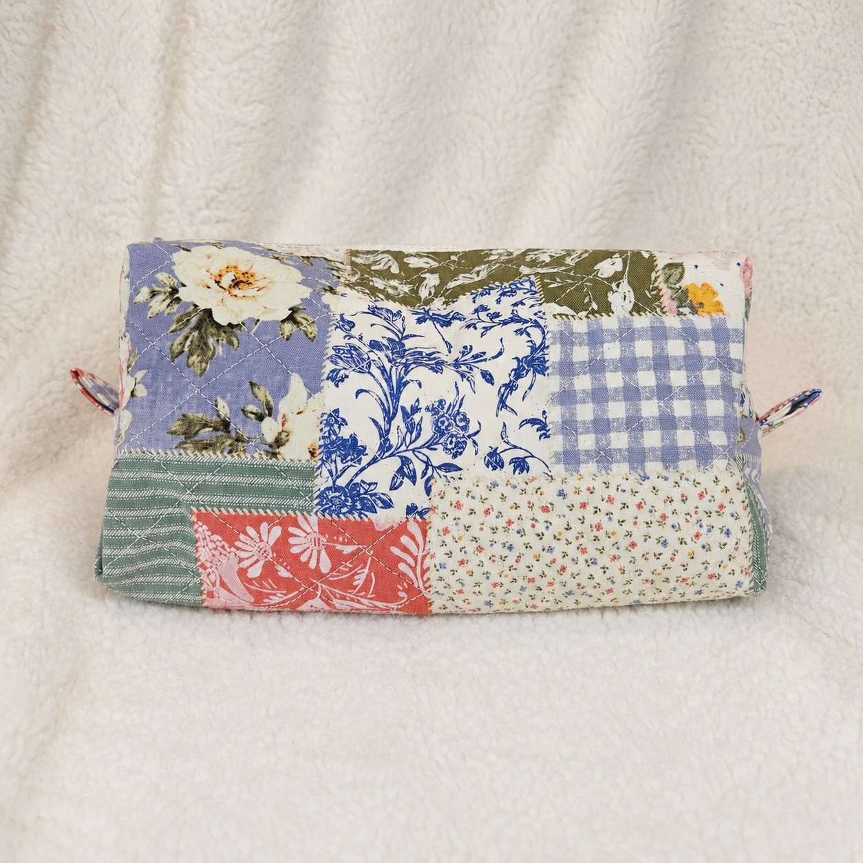 Patchwork fabric pouch with floral and checkered patterns on a beige background