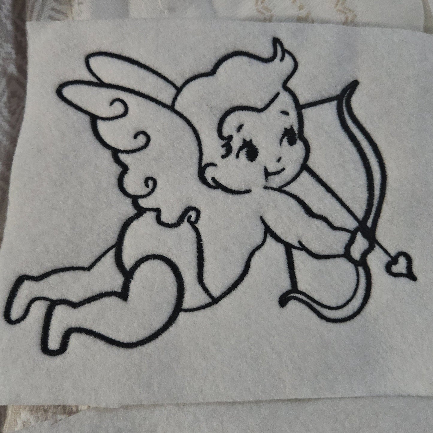 Embroidered design of a cupid on a white background