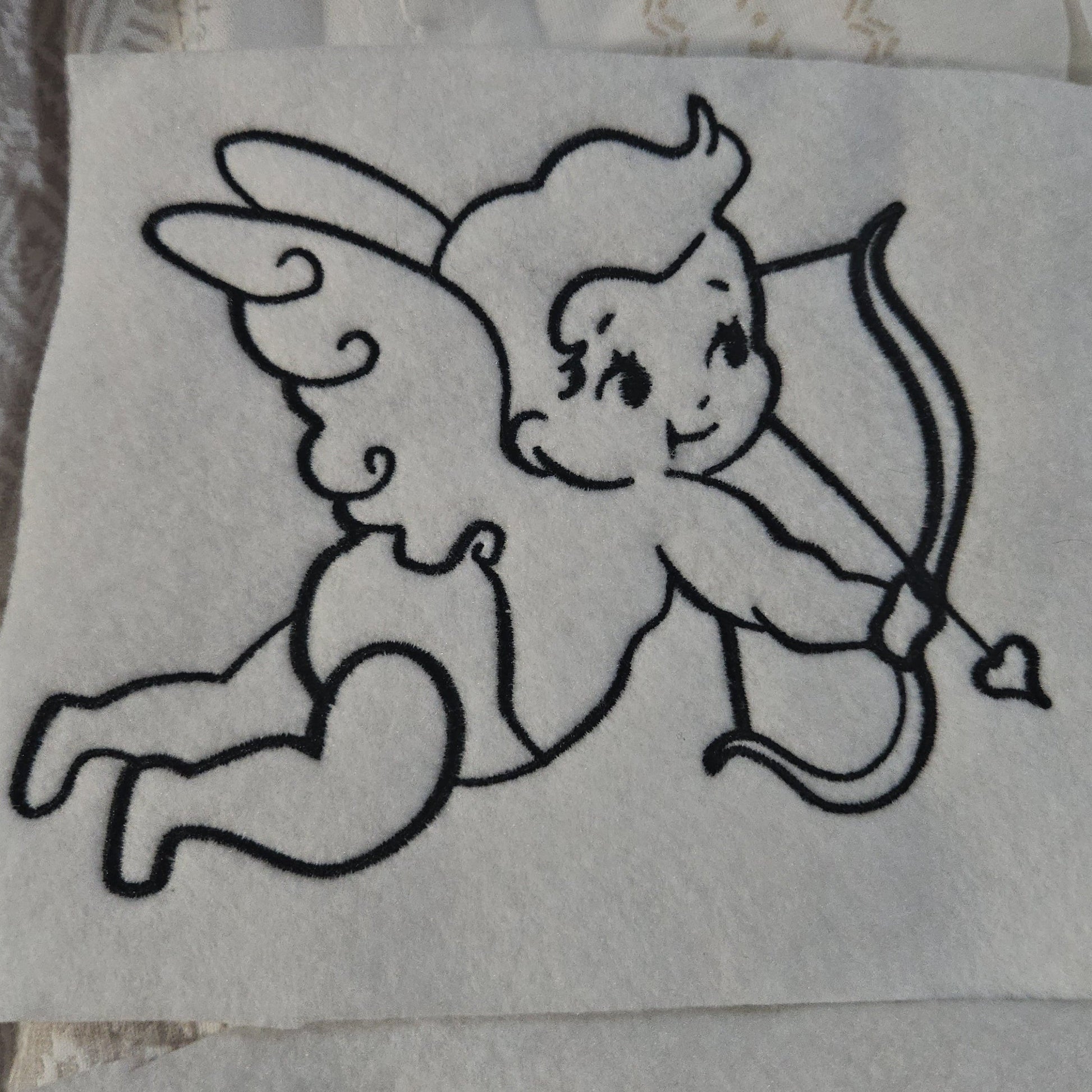 Embroidered design of a cupid on a white background