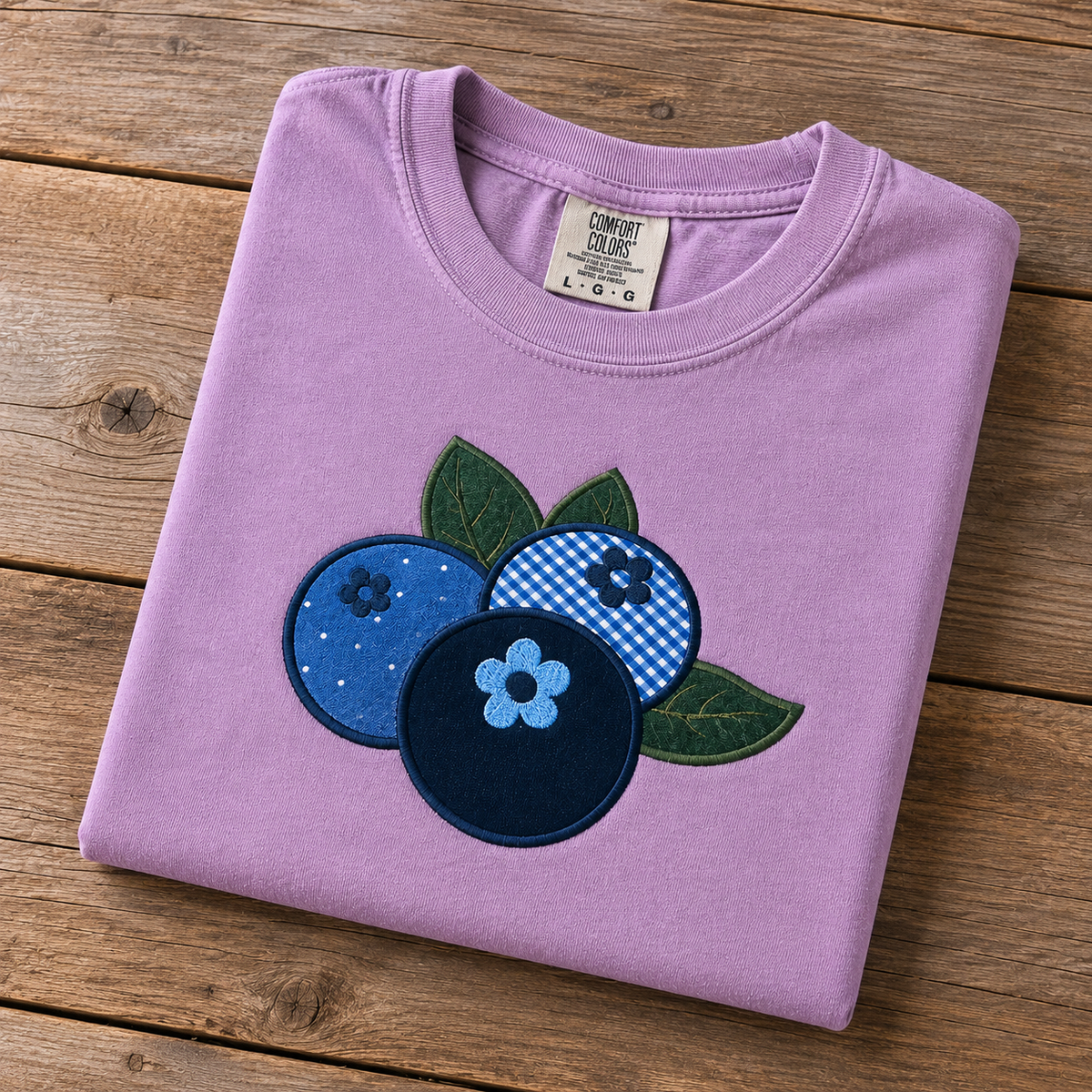 Folded orchid t-shirt with blueberry design on a wooden surface