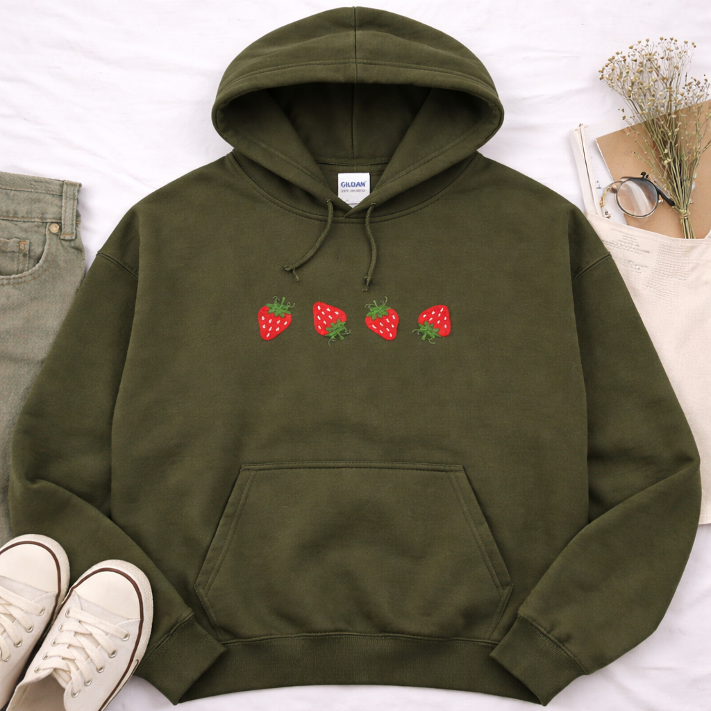 Military green hoodie with strawberry design on a white surface with jeans and sneakers.