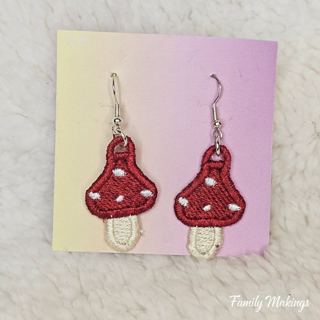Embroidered mushroom earrings with silver posts on a card