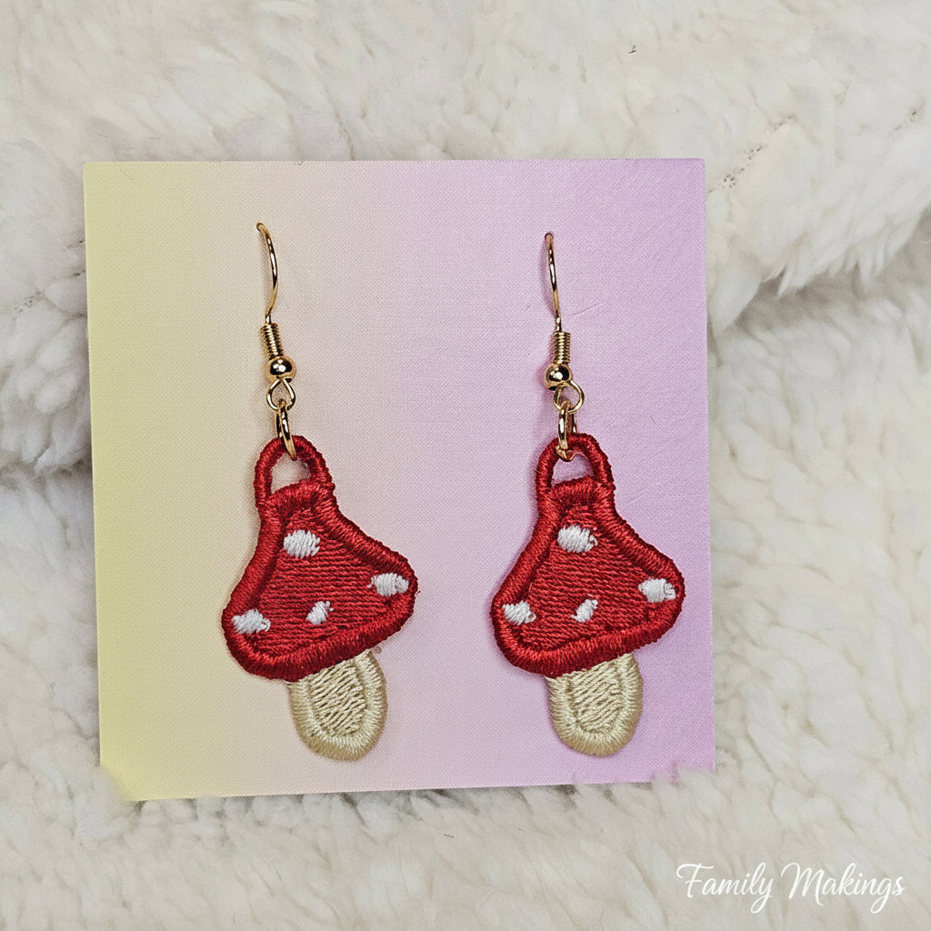 Embroidered mushroom earrings with gold posts on a card