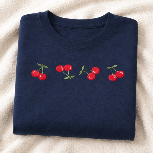 Folded navy shirt with red cherry design on a white surface